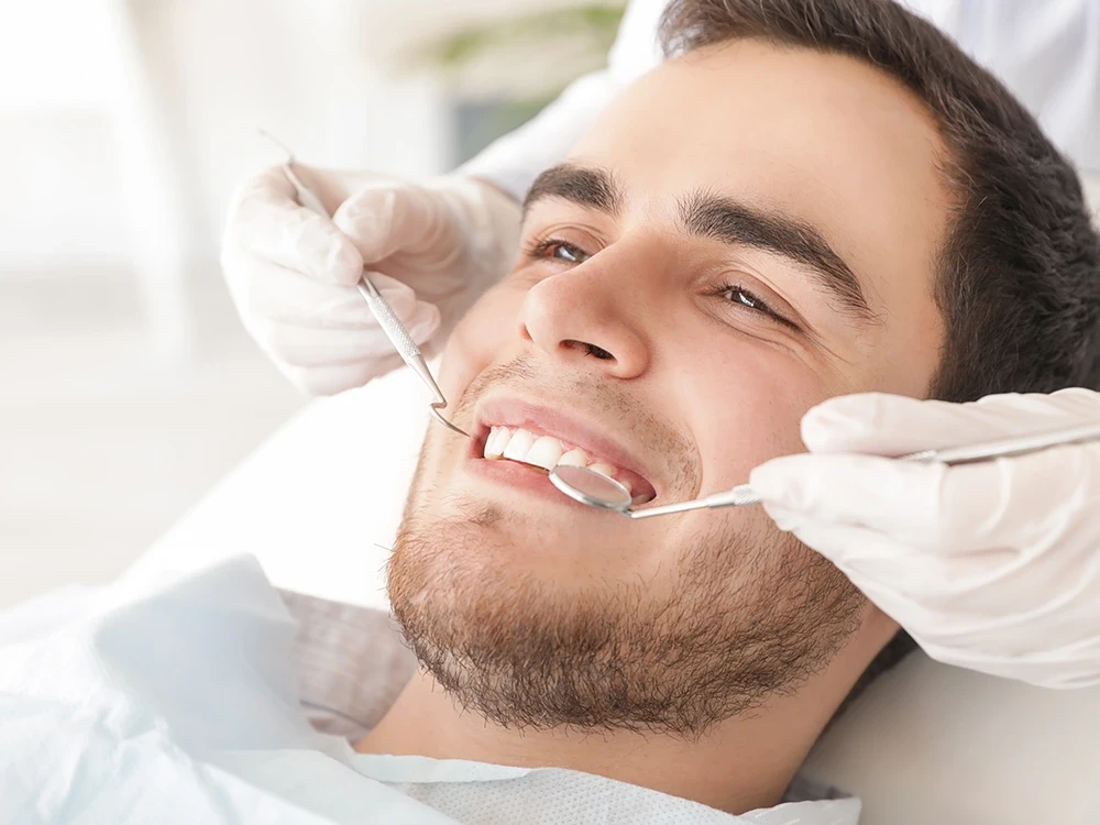 Мужчина лечит зубы перед установкой виниров